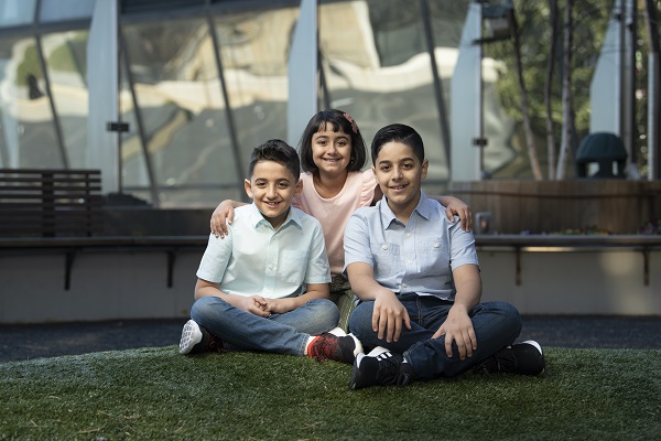 3 kids sit on grass
