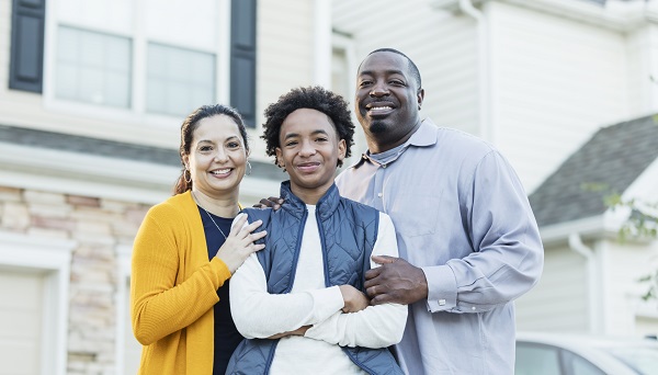 Parents stand behind their teenage son with their hands on his arms.