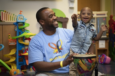 Noah points and smiles in a play room